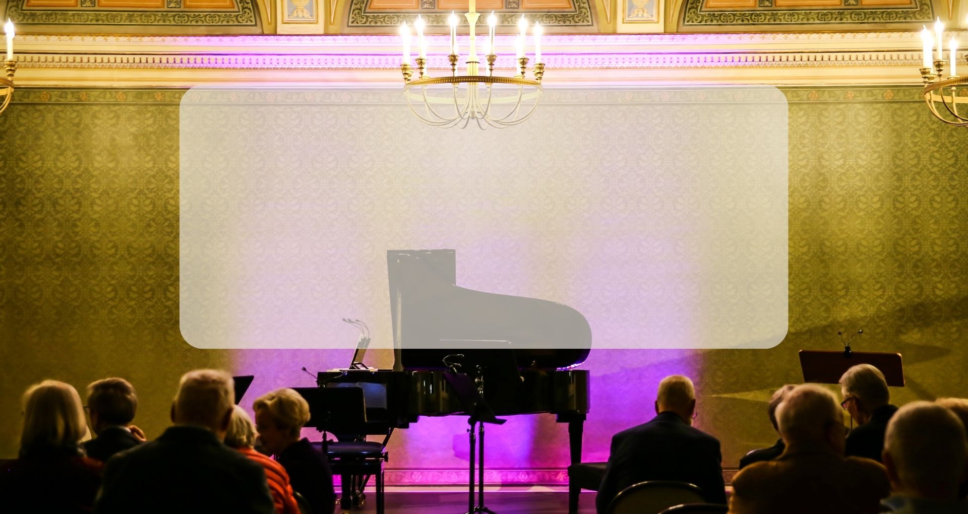 Im Konzertsaal des Schloss Winnenden steht ein Flügel vor den Zuschauerinnen und Zuschauern. Darüber hängt ein Kronleuchter